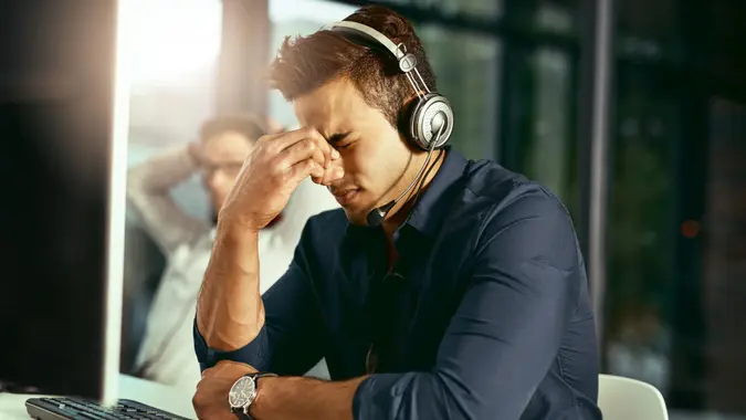 Shot of a young call centre agent looking stressed out while working in an office.