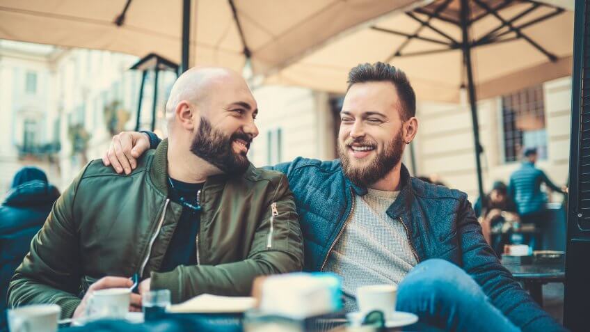 Two Smiling Handsome Friend Drinking Coffee and Talking at Favorite Coffee Place.