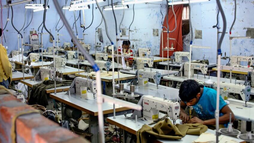 unidentified tailors sewing some clothes in a factory near ludhiana, punjab, india on 10 october 2013.
