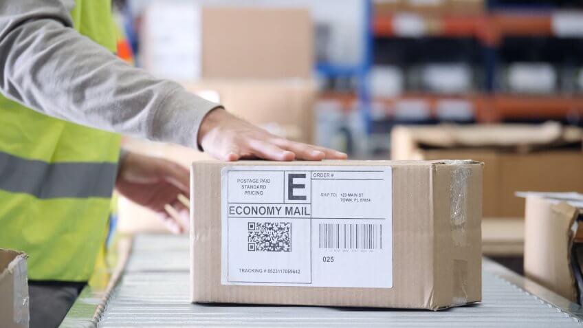 Unrecognizable distribution warehouse employee places a hand on a package ready for distribution.