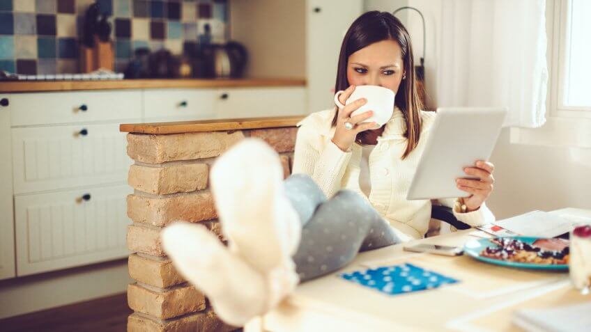 Beautiful youngBeautiful young woman is having breakfast in the kitchen while online shopping woman is having breakfast in the kitchen.