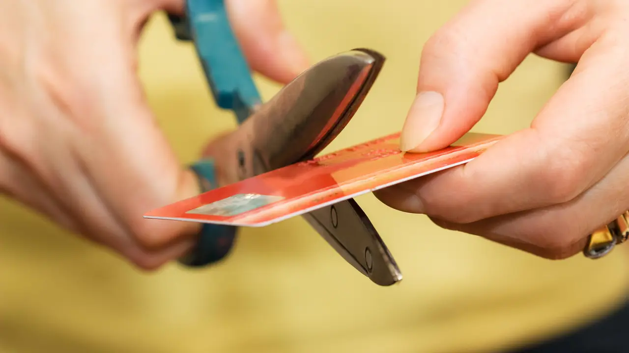 Close-up of Female hands cutting a credit card with a scissors.