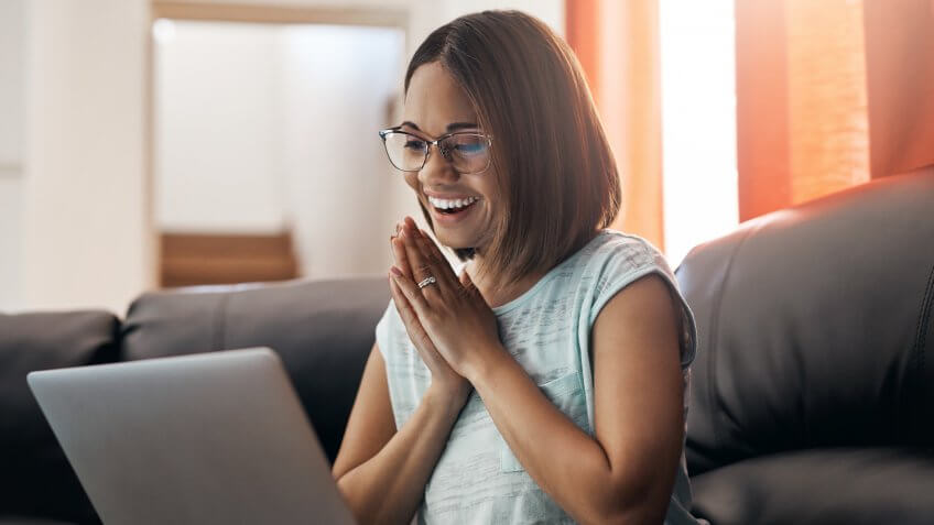 attractive young woman using a income calculator on laptop at home.