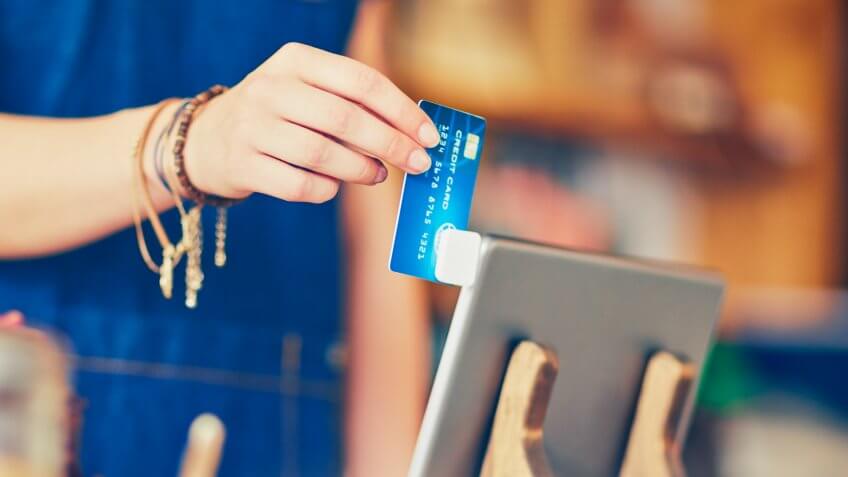 female swiping credit card using digital tablet.