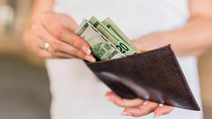 People, business, finances and money concept - close up of businesswoman hands holding open wallet with dollar cash.