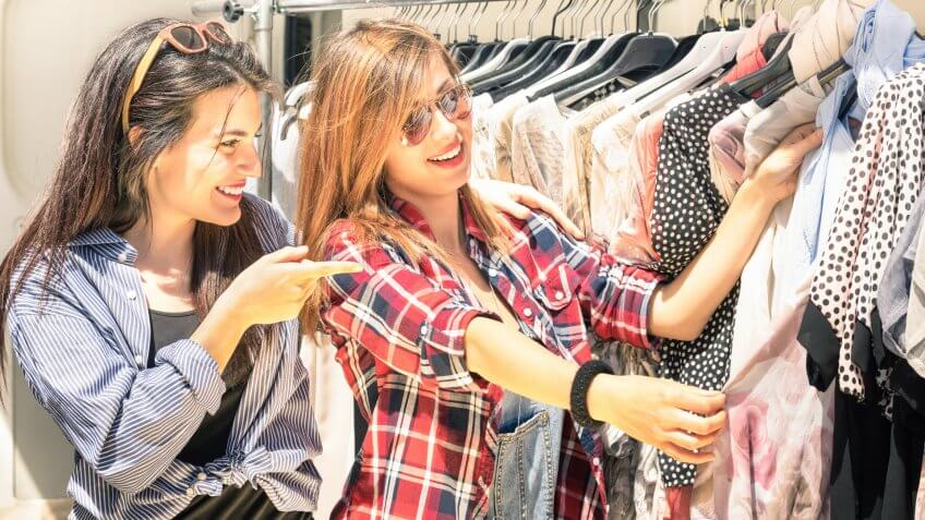 Young beautiful women at the weekly cloth market - Best friends sharing free time having fun and shopping in the old town in a sunny day.