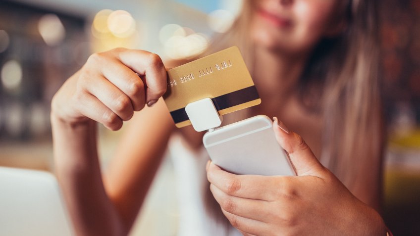 Woman in cafe making mobile payment with credit card