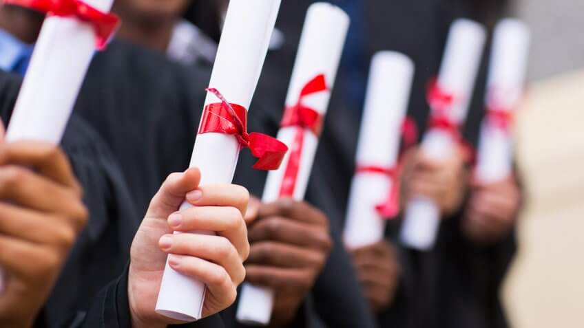 diverse group of graduates holding diplomas