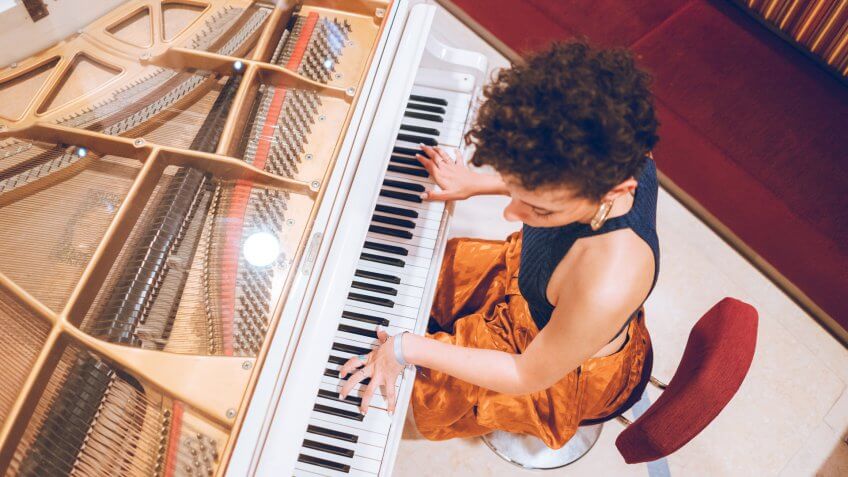 Young beautiful caucasian woman plays piano.