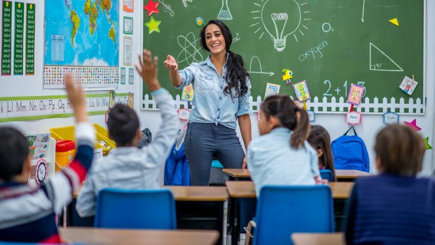 An Ethnic teacher is leading a class of elementary school children.