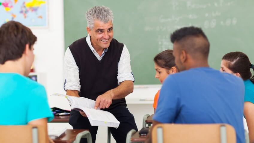 senior high school teacher teaching group of students in classroom.