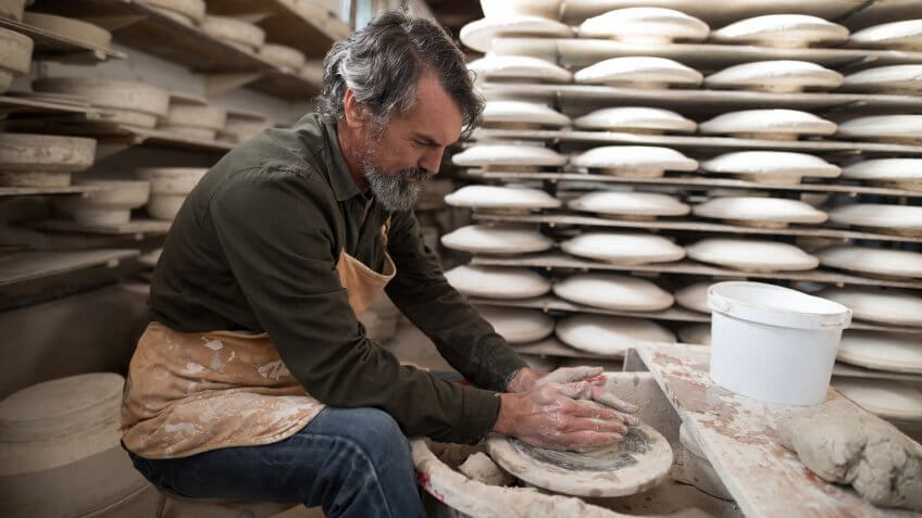Male potter molding a clay in pottery workshop.