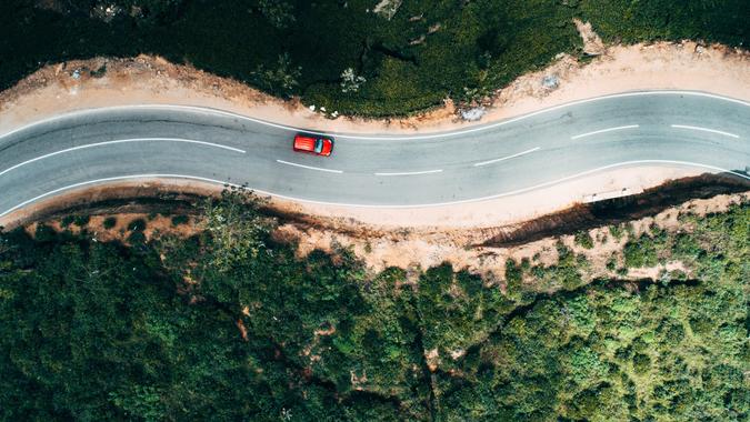 Aerial view on  red car on the road near green tea plantation in mountains in Sri Lanka.