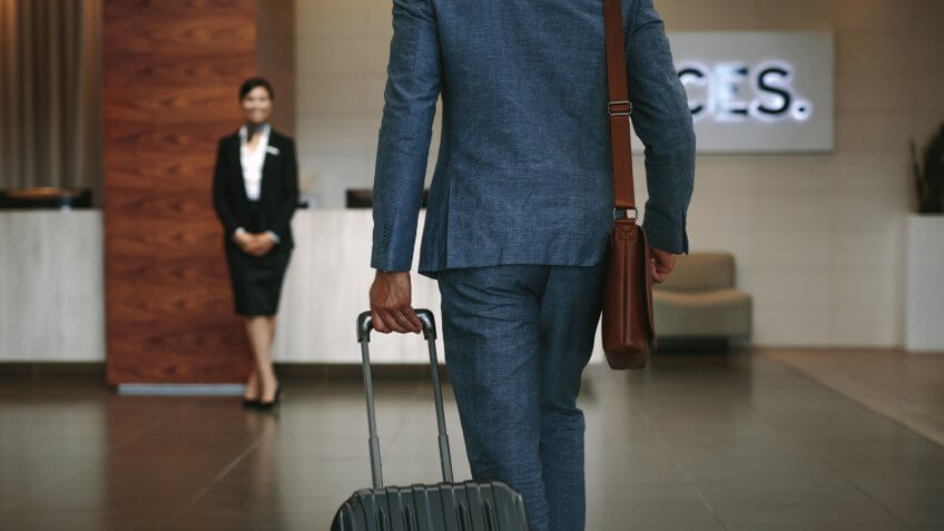 Businessman carrying suitcase while walking in hotel lobby.