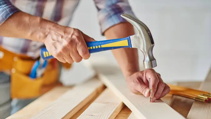 Carpenter with hammer hitting nails.