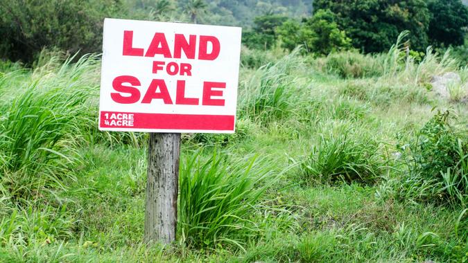 land for sale sign in grassy lot.