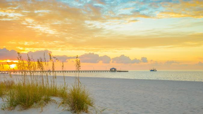 Gulfport Mississippi beach, dramtic golden sunrise, pier, shrimp boat, on the Gulf of Mexico.