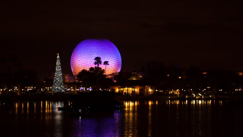 Orlando, Fl, USA- December 9, 2015: Spaceship Earth illuminated at night with large Christmas tree viewed from the world showcase in Disney World's Epcot amusement park.