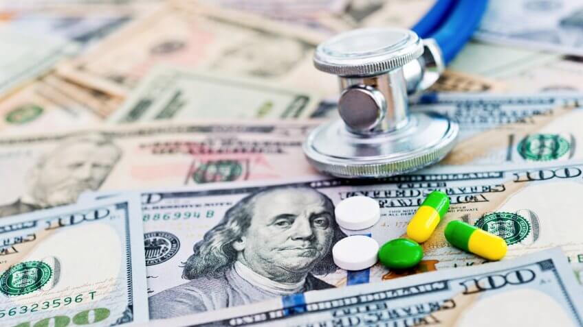 Stethoscope and pills on US dollar bills.