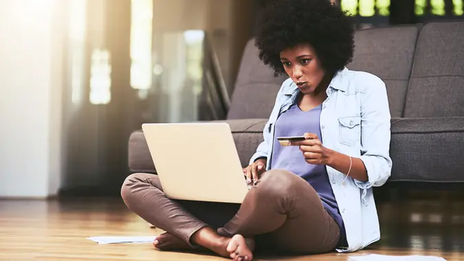 Shot of a young woman using a laptop and credit card at home.