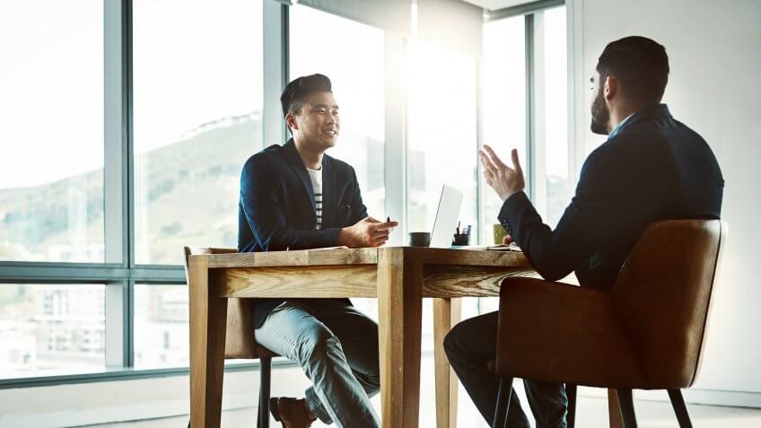 Shot of two young businessmen having a discussion at a desk in a modern office.