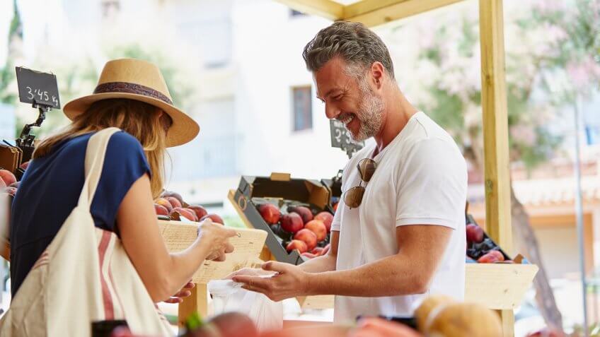 Mature couple buying fruits while standing by crates in store.