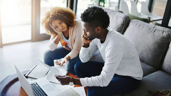 Shot of a young couple looking anxious while doing their budget at home.
