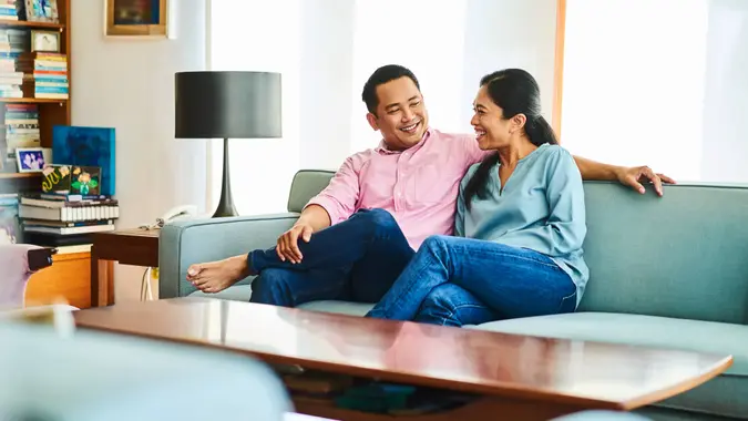 Smiling mature couple sitting on sofa at home.