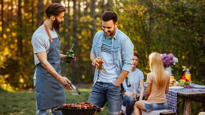 Two young man making barbecue outdoors.