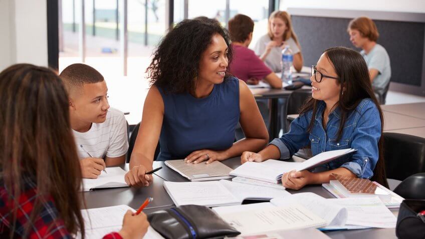 Teacher studying school books in class with high school kids.