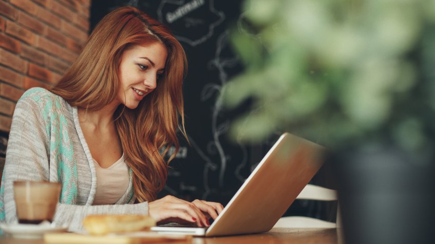 Young woman typing on laptop in cafe.