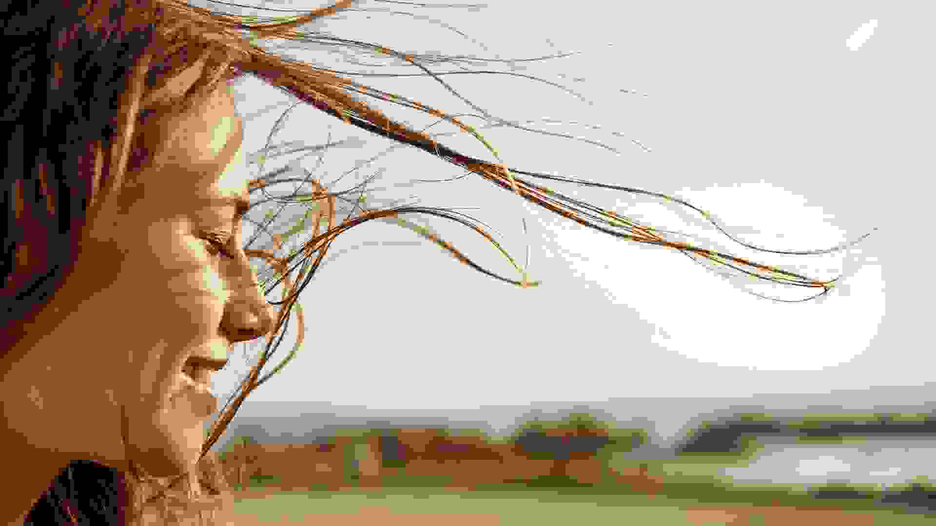 Cropped view of a young woman with the wind in her hair.