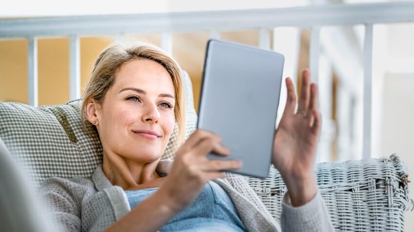 A photo of happy young woman using digital tablet on balcony.