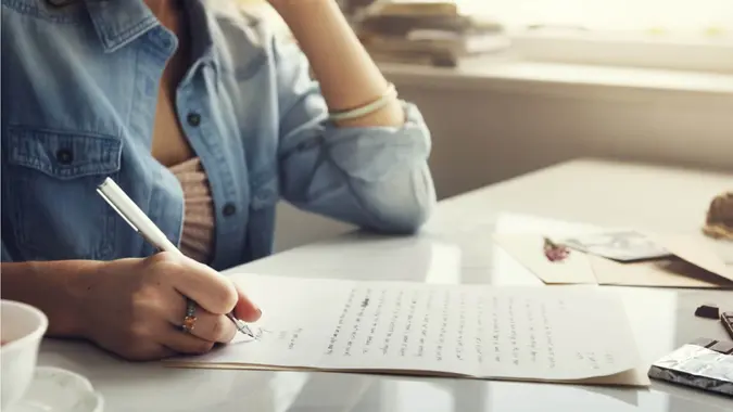 A woman sitting at a desk and writing a letter.