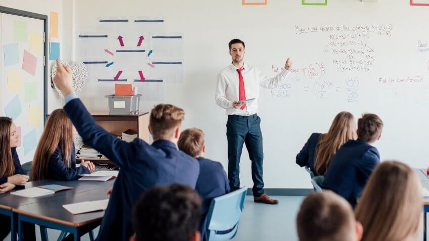 Teenage female student raising her hand to answer a question.