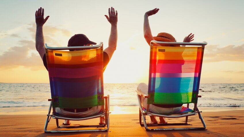 man and woman sitting on beach chairs at sunset