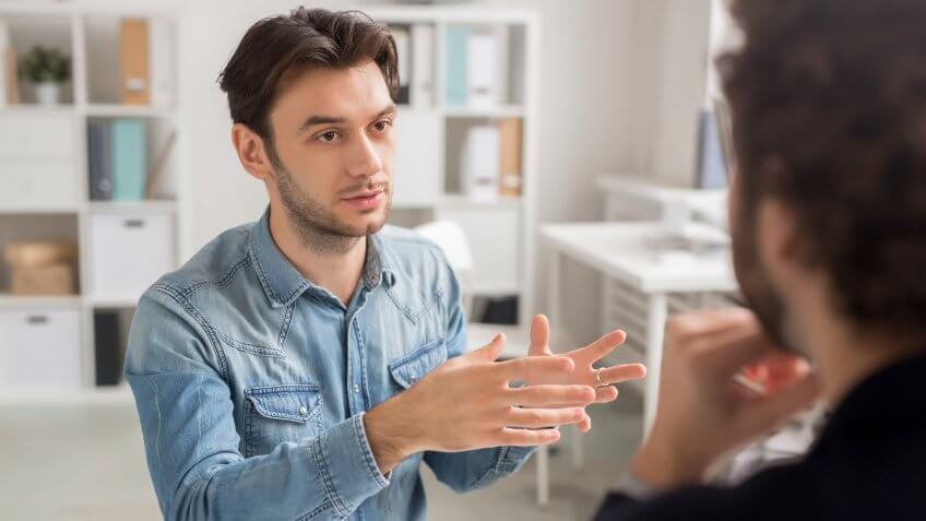 Serious successful young manager explaining his idea to boss or giving more details about preparation of project.