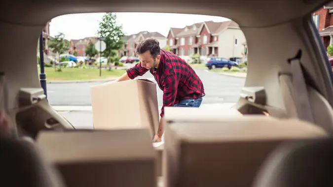 Caucasian man loading moving boxes in to his car.
