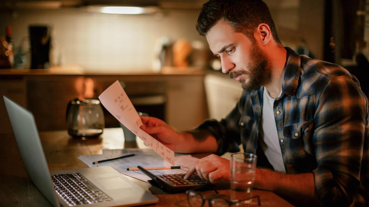 Photo of a stressed man going trough his financials problems,he is sitting in kitchen late at night checking and paying bills.