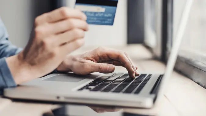 Men entering credit card information using laptop computer.