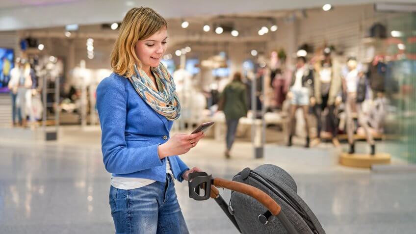 mom with stroller and smartphone walking in a mall