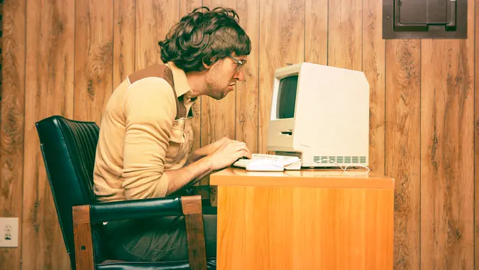 Goofy 1980s Computer Worker looking intently at a vintage computer screen.