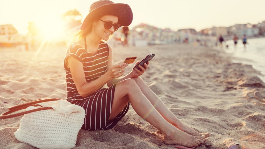 Woman at the beach using credit card for online shopping +++++ Note for the inspector : Credit card is fake and is made especially for the photosession +++++.
