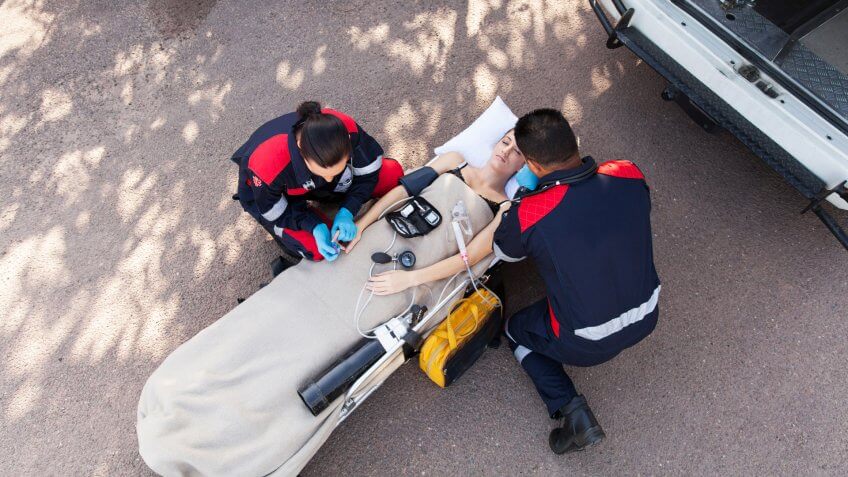 paramedic team providing first aid to unconscious woman