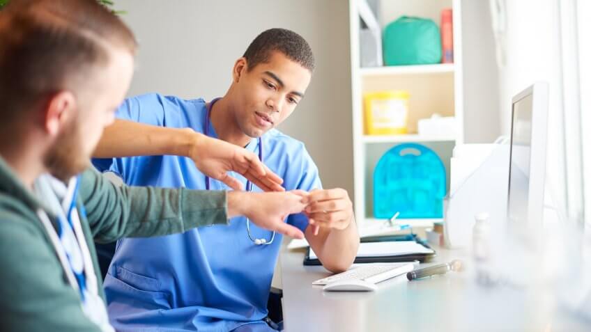 gp examines male patients hand.