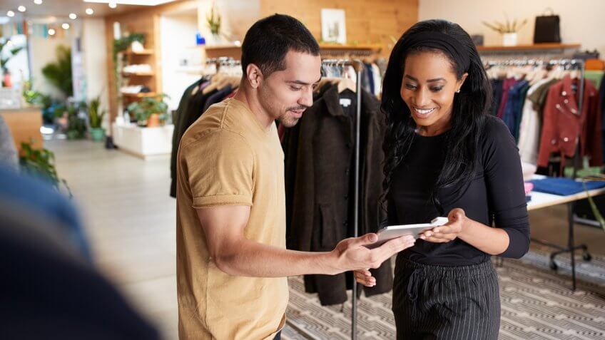 Smiling couple using tablet computer in a clothes shop.