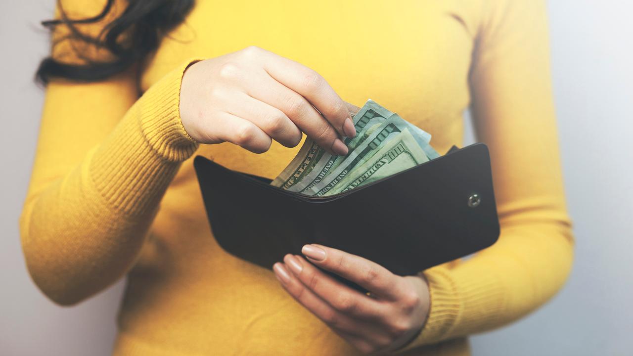 woman taking dollars money from black wallet.