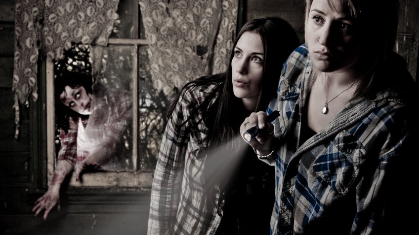 two girls in haunted house with scary zombie