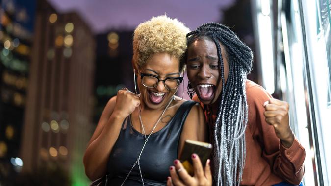 two women excited about good news on their smartphone