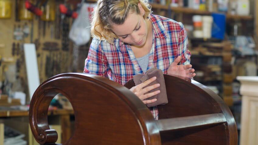 woman polishing wooden object in workshop